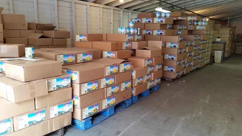 Stacks of cardboard boxes on blue pallets inside a storage warehouse.